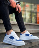 White sneakers with blue accents worn by a person sitting on steps.