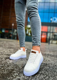 White sneakers worn with light gray jeans on a textured pavement.