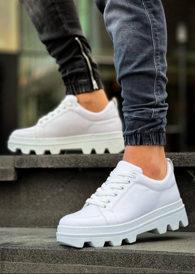 White sneakers with thick soles worn by a person on steps.