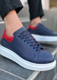 Navy blue sneakers with red accents worn by a person on a tiled floor.