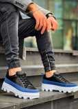 Black and blue sneakers with white soles worn by a person on steps.