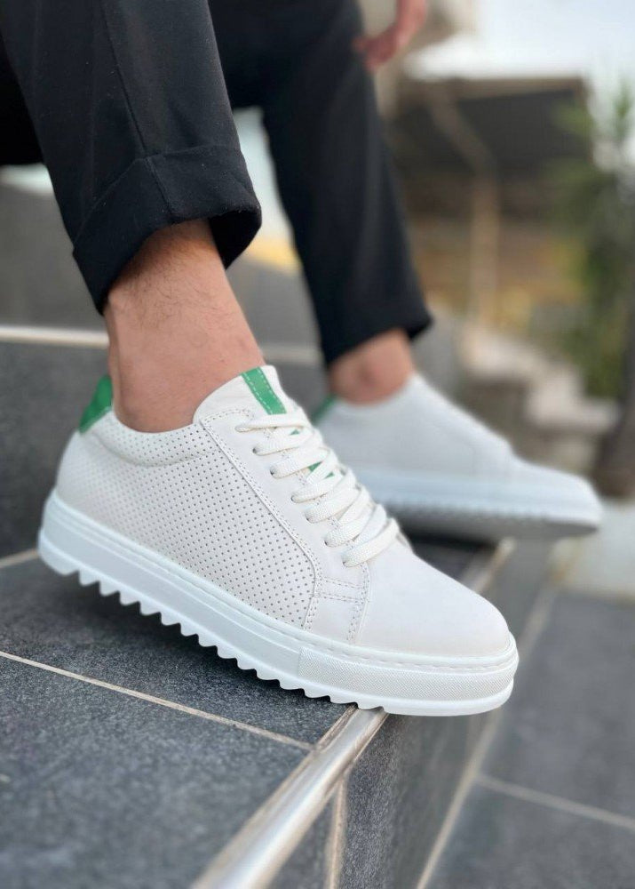 White sneakers with green accents worn by a person on a stone surface.