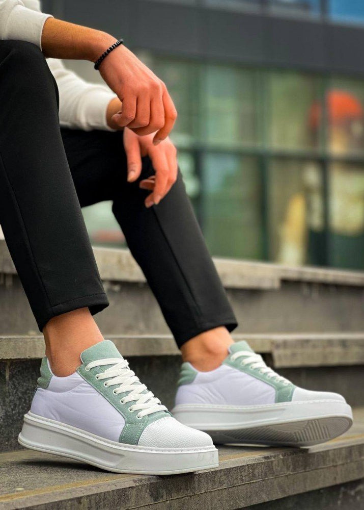 White and green sneakers worn by a person sitting on steps.