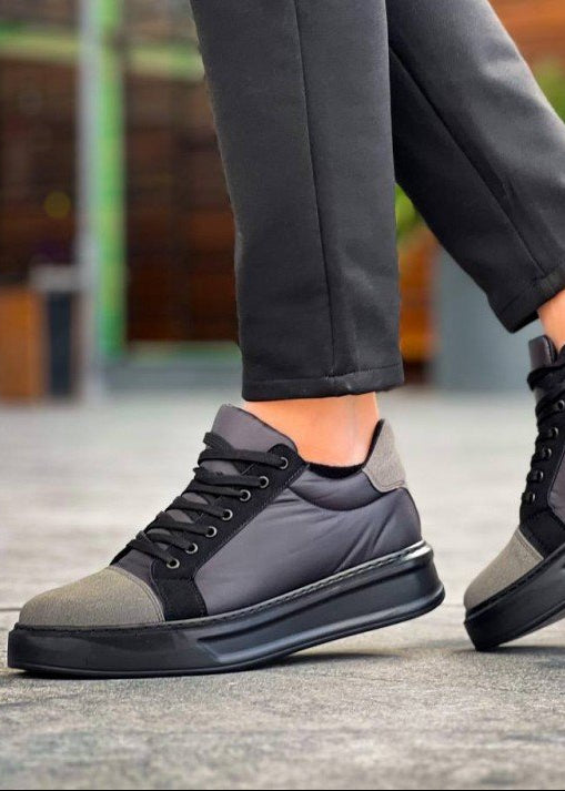 Gray and black sneakers worn by a person on a blurred outdoor background