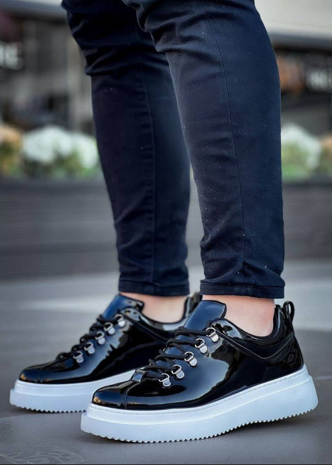 Black and white sneakers worn with dark pants on a blurred outdoor background